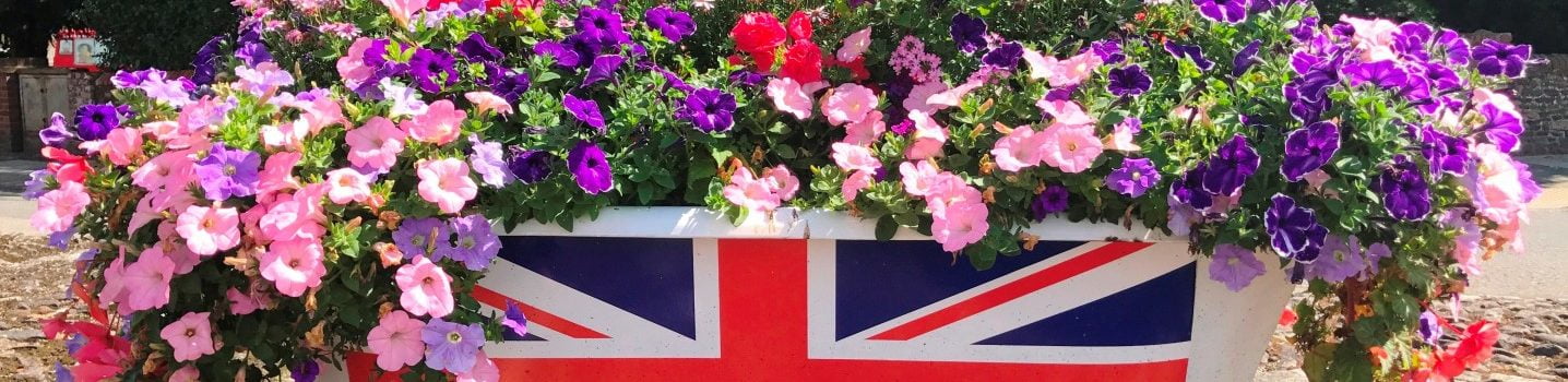 Bath tub with Union flag on side and filled with pink and purple flowers