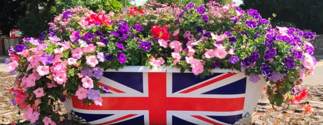 Bath tub with Union flag on side and filled with pink and purple flowers
