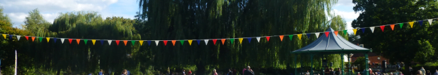 Colourful bunting, crowd, trees and bandstand in background.