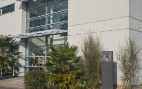 Outside of a white modern building with small trees in front