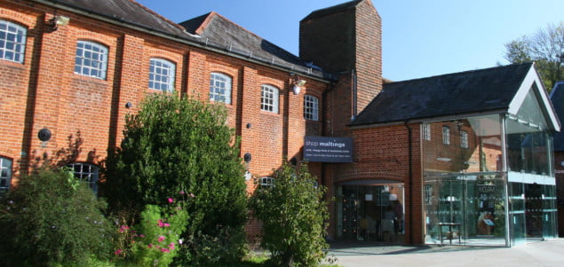 Red brick building with gardens in front and a glass porch