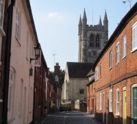 Pathway with brick houses on the left and right side and church in the background.