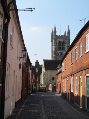 Pathway with brick houses on the left and right side and church in the background.