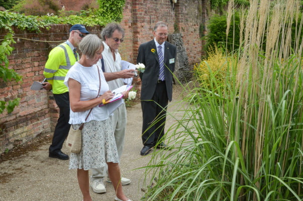 Male and female with clipboards looking at plants in garden.