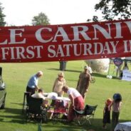 Banner advertising Hale Carnival. People setting up stalls for fete.