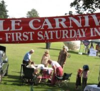 Banner advertising Hale Carnival. People setting up stalls for fete.