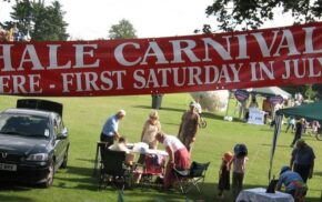 Banner advertising Hale Carnival. People setting up stalls for fete.