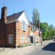 exterior of red brick building, flags and clock on the side.