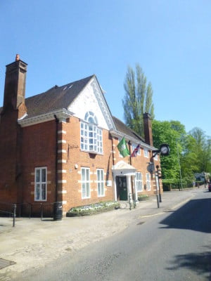 exterior of red brick building, flags and clock on the side.