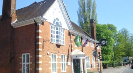 exterior of red brick building, flags and clock on the side.