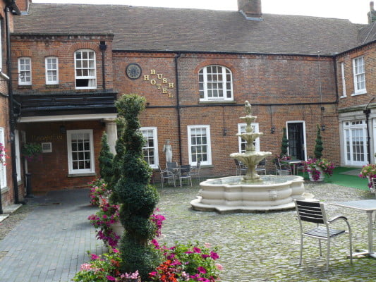 courtyard with brick building and stone fountain in the center, decorative plants around the edge.