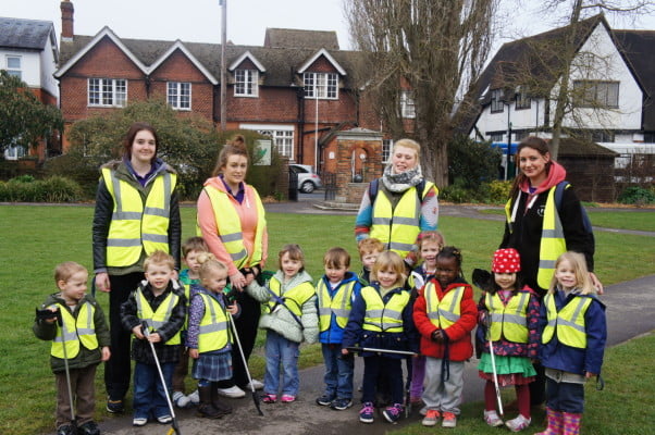 Group of boys, girls and four women with high vis vests in park.