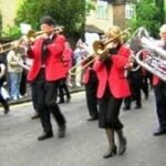 Group of people with brass instruments, all dressed in black and red.