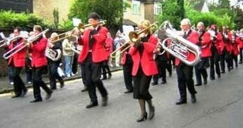 Group of people with brass instruments, all dressed in black and red.