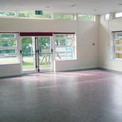 interior of white hall, large windows and fire doors to the left.