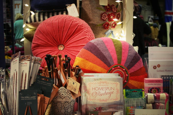 Display of colourful round knitted cushions and knitting accessories