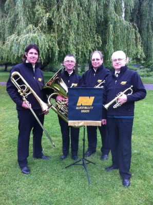 Four male members of brass band. Music stand. Brass instruments.