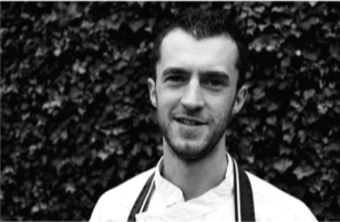 Black and white head and shoulders photo of man wearing chef's whites. © The Wheatsheaf Pub & Grill