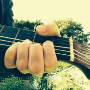 Hand, guitar neck, sky, trees.