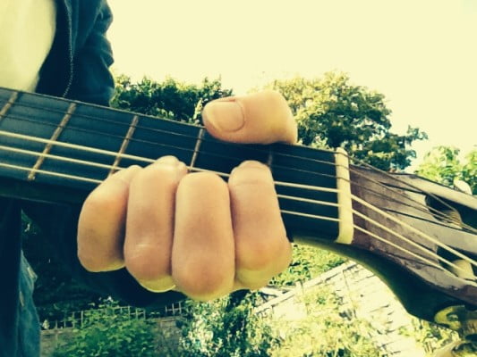 Hand, guitar neck, sky, trees.