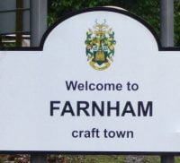 Road sign, with black writing and town council crest.