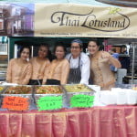 Five people behind stall serving food.