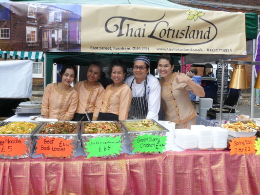 Five people behind stall serving food.