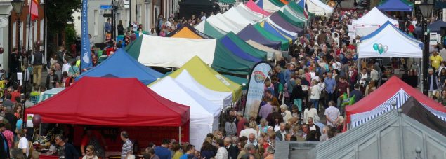 Aerial view of people and colourful market stalls at Food Festival held in street.