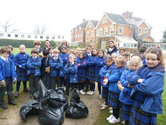 Group school children, blue uniform, litter pick, sacks of rubbish, school