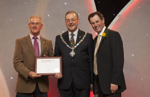 Three males holding certificate.