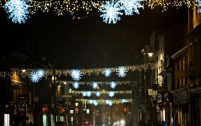 Across street Christmas lights.White stars and gold lights. Busy street. Nighttime.