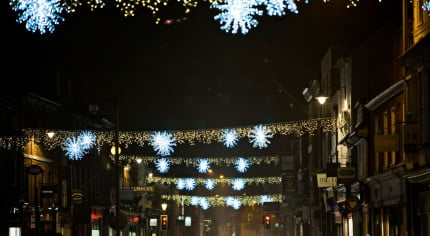 Across street Christmas lights.White stars and gold lights. Busy street. Nighttime.