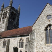 Stone church with red tiled roof. Tower, arched windows