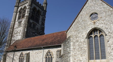 Stone church with red tiled roof. Tower, arched windows