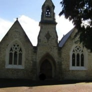 Outside stone chapel, bell turret, arched windows and door.