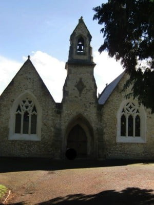 Outside stone chapel, bell turret, arched windows and door.