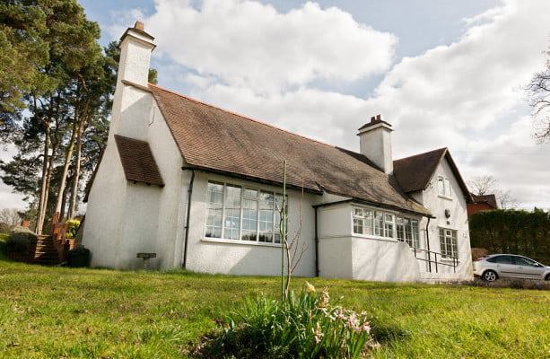 Front of village hall with white walls, tiled roof and chimney on left hand side of building