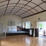 Inside view of village hall. White domed ceiling, wooden floor and large windows on right hand side