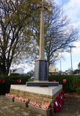 Stone war memorial with poppies at base.