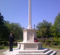 Man standing to attention on step of war memorial