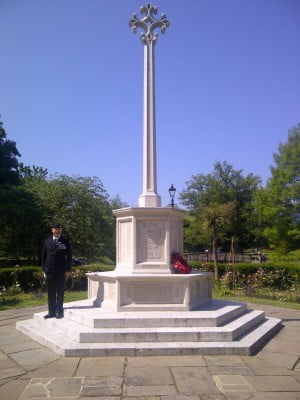 Man standing to attention on step of war memorial