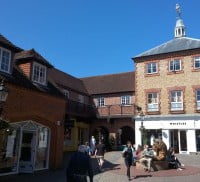 shops, cobbled streets, people walking around. Lion statue to the right.