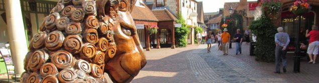 Wooden lion sculpture in pedestrianised shopping street.