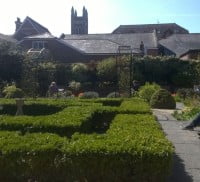 green hedges, footpaths, one male and one female sitting on a bench talking.