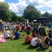 Crowd of people in park, with stage and bunting