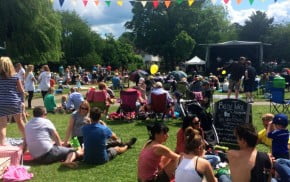 Crowd of people in park, with stage and bunting