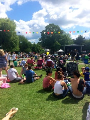 Crowd of people in park, with stage and bunting
