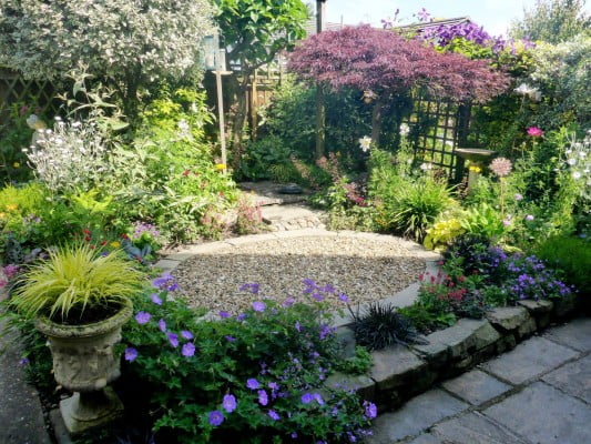 Courtyard garden in the summer. Gravel in the middle, surrounded by plants.