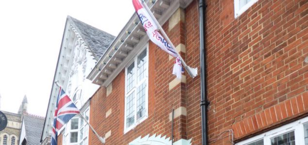 two flags outside of a redbrick building.