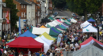 Brightly coloured marquees in street and crowds of people